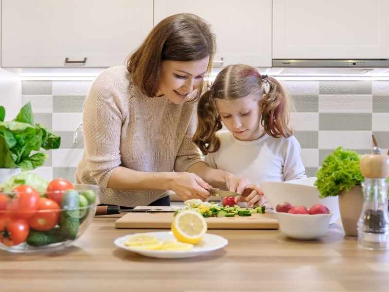 Familia prepara alimentos saludables en casa como parte del bienestar infantil.