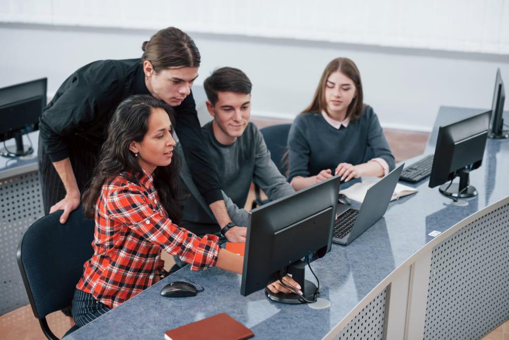 Imagen de estudiantes con tecnología educativa en un aula moderna colaborando con profesionales