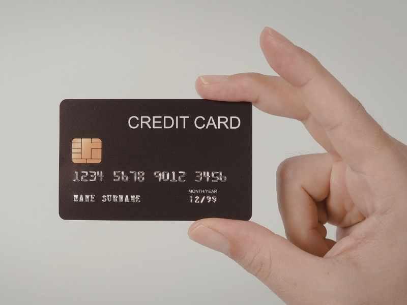 Mano sosteniendo una tarjeta de crédito, relacionada con pago total vs pago mínimo y compras a cuotas.