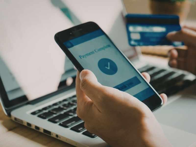 Persona usando el celular junto a una laptop para revisar cuotas y organizar pagos en un tablero único.