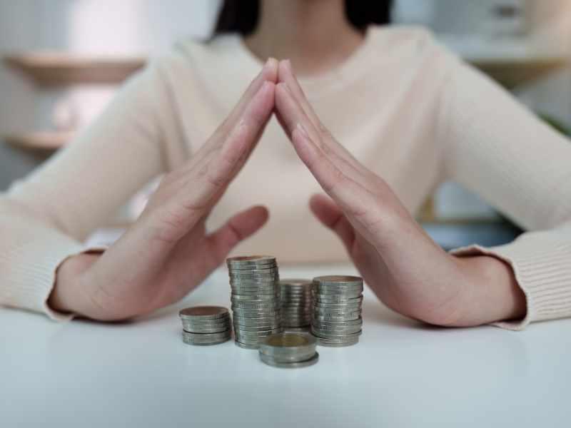 Manos juntadas frente a pilas de monedas, representando control de gastos y presupuesto en Guatemala.